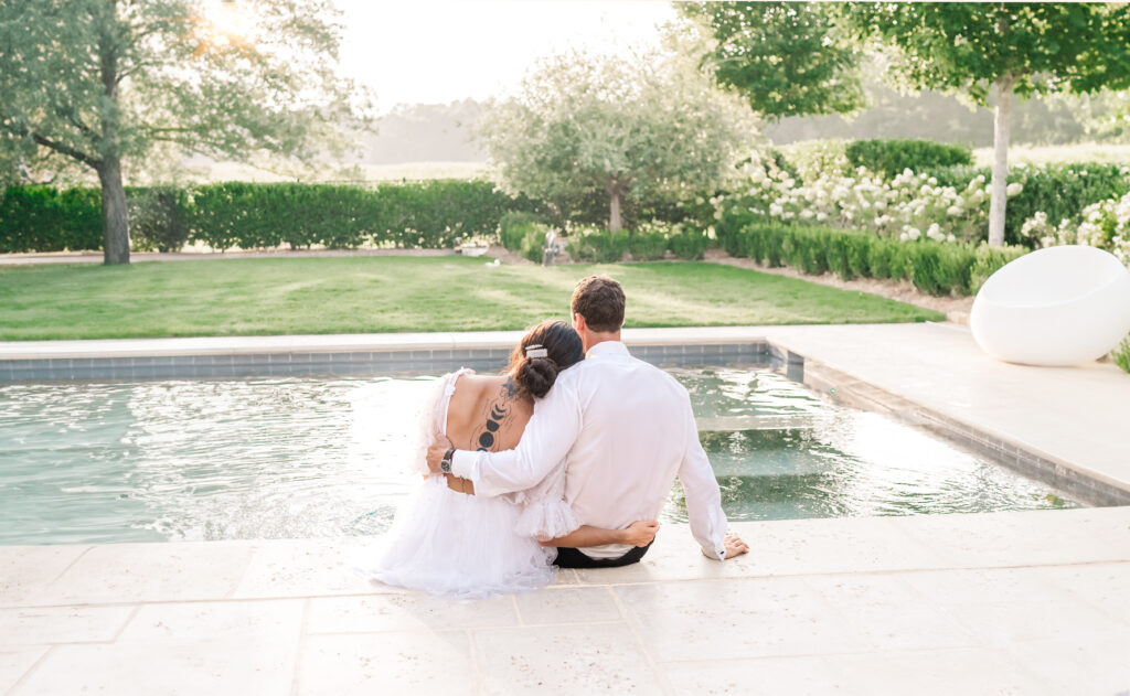 A couple embracing at sunset next to the pool during the fall at an elegant Raleigh estate by JoLynn Photography