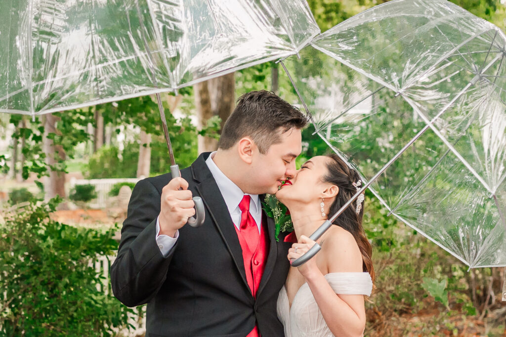 A happy couple kissing in the rain during their fall wedding near Raleigh by JoLynn Photography