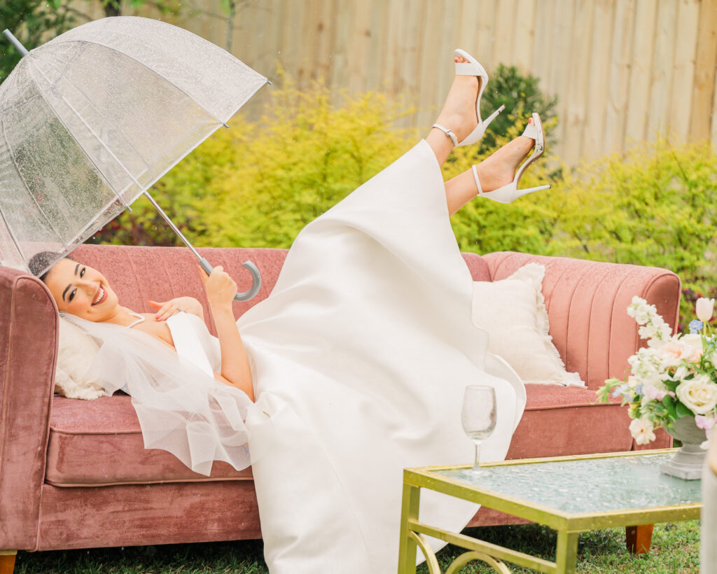 A happy bride playing in the rain during her Raleigh wedding bridal portrait session by JoLynn Photography