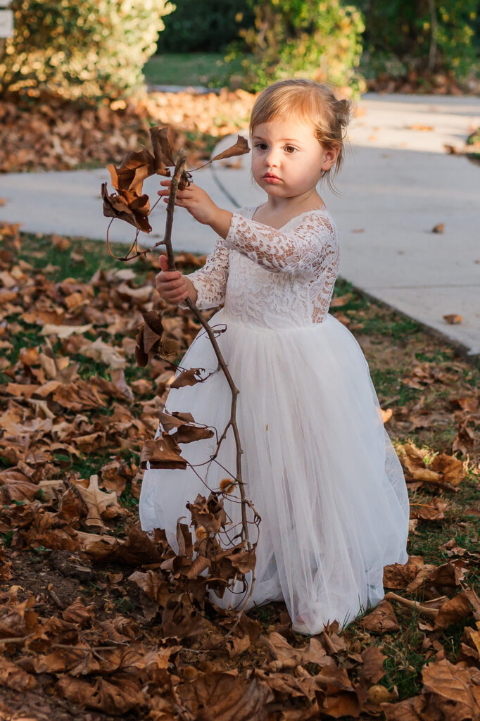 A precious flower girl playing with the leaves at the Hudson Manor