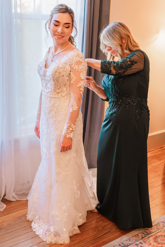 A bride and her mom getting ready during her wedding day at the Hudson Manor