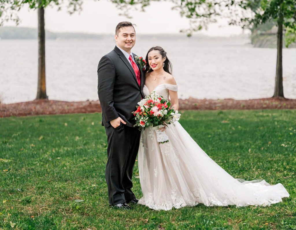 A happy Asian couple at sunset overlooking the water at their Lake Gaston wedding by JoLynn Photography