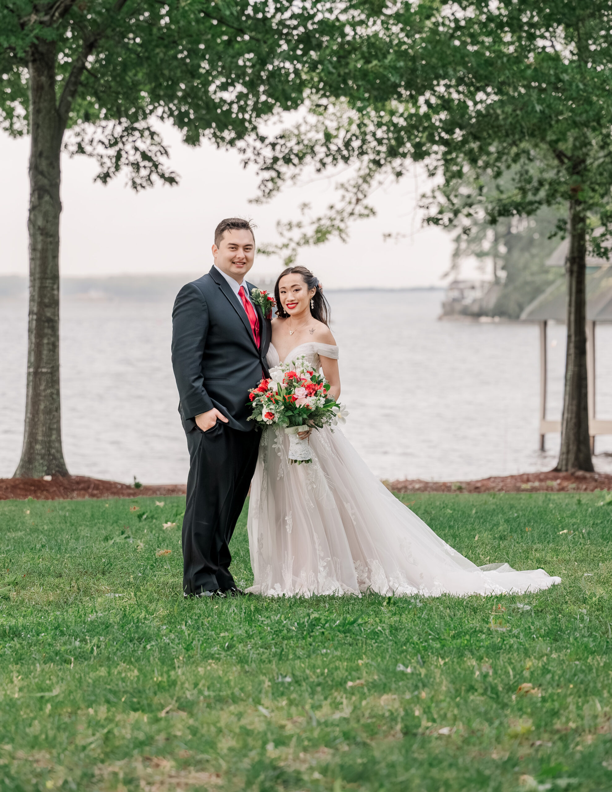 A happy Asian couple on a waterfront property celebrating their Lake Gaston wedding by JoLynn Photography
