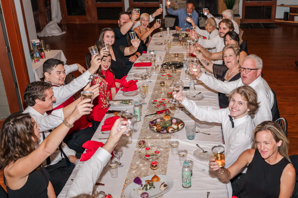A happy wedding party celebrating at dinner at a Lake Gaston Wedding by JoLynn Photography