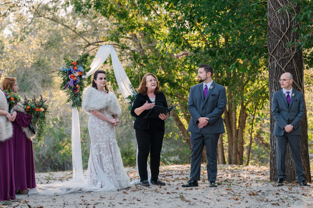 A couple exchanging vows during sunset at the River Landing wedding venue by JoLynn Photography