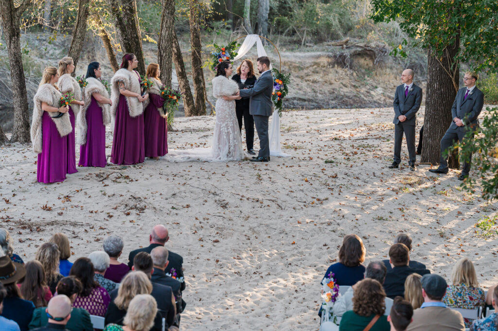 A couple holding hands and exchanging vows at the River Landing wedding venue by JoLynn Photography

