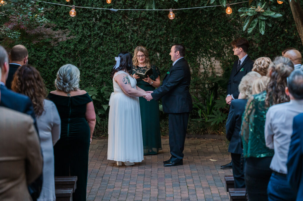 A bride and groom saying their wedding vows in front of their friends and family at The Atrium Wedding Venue by JoLynn Photography