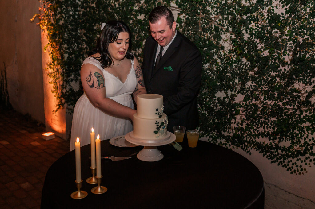 A bride and groom cutting their wedding cake by JoLynn Photography