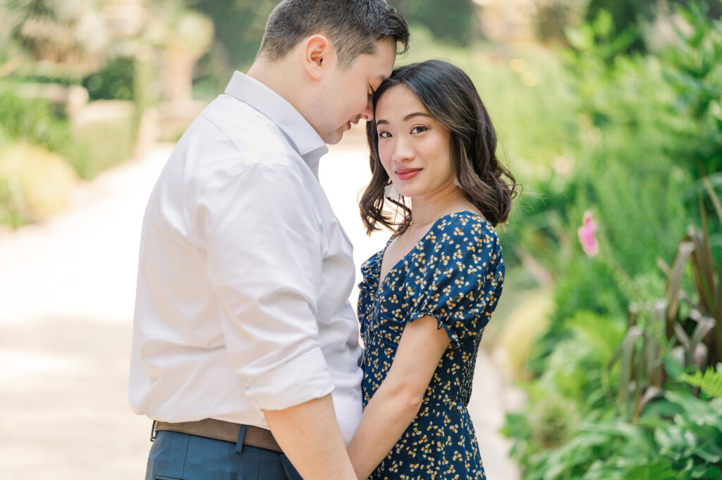 A loving Asian couple celebrating their engagement at a Wilmington park by JoLynn Photography