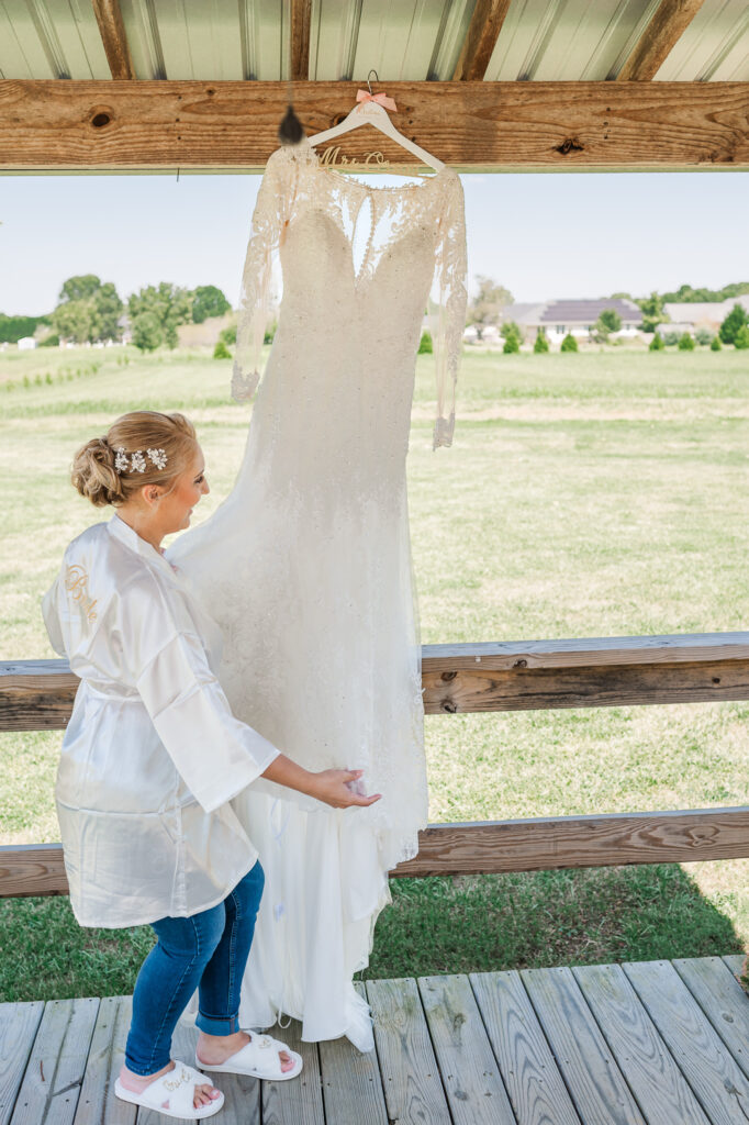 A bride looking at her wedding dress at Boots and Roots Farm by JoLynn Photography
