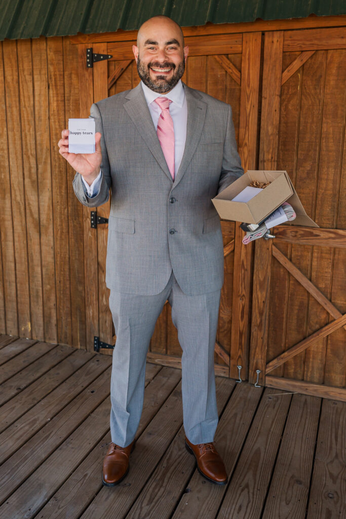 A groom showing a wedding gift his soon-to-be wife made for him on his wedding day in the Raleigh countryside