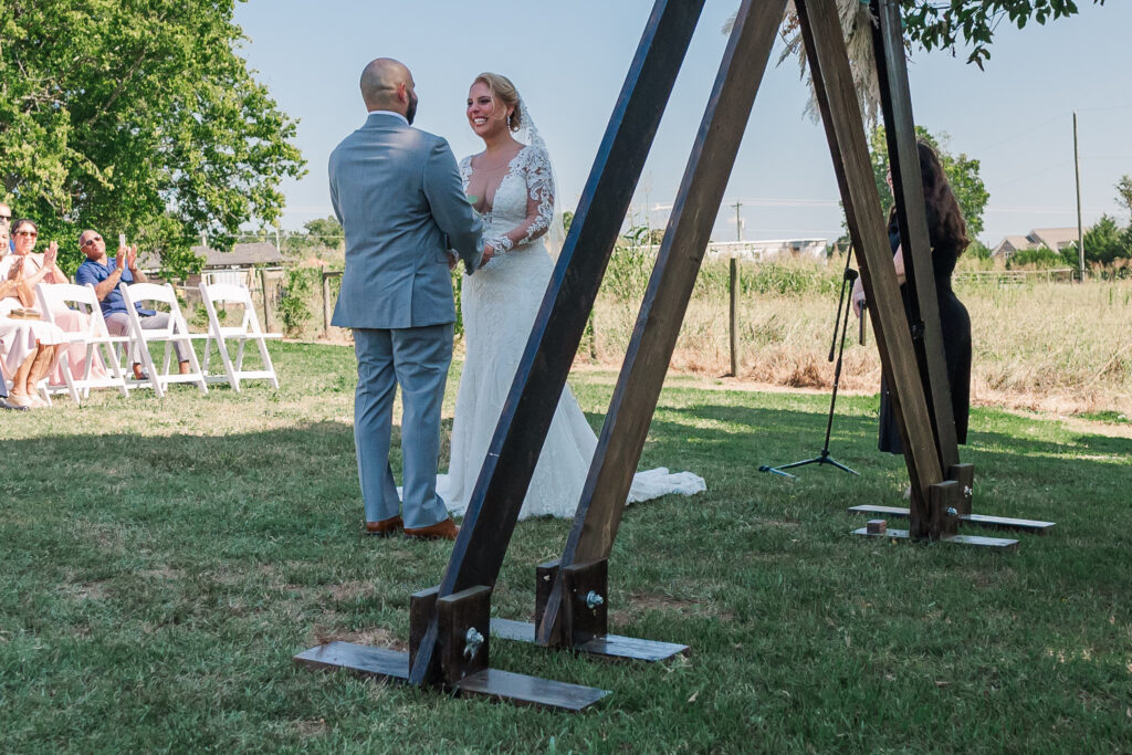 A bride and groom laughing as they say their vows at Boots and Roots Farm by JoLynn Photography