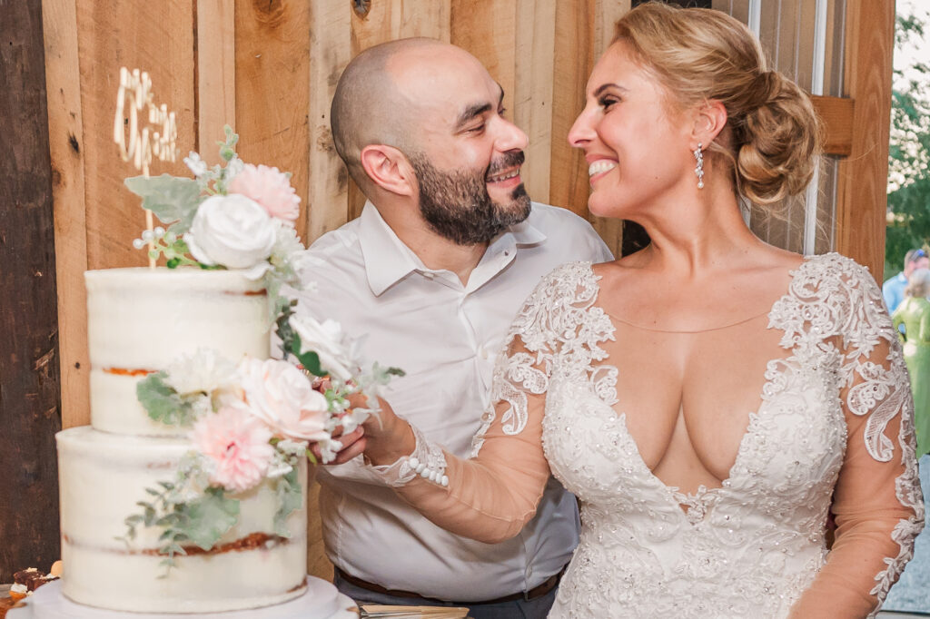 A newly wed couple cutting their wedding cake in a barn by JoLynn Photography