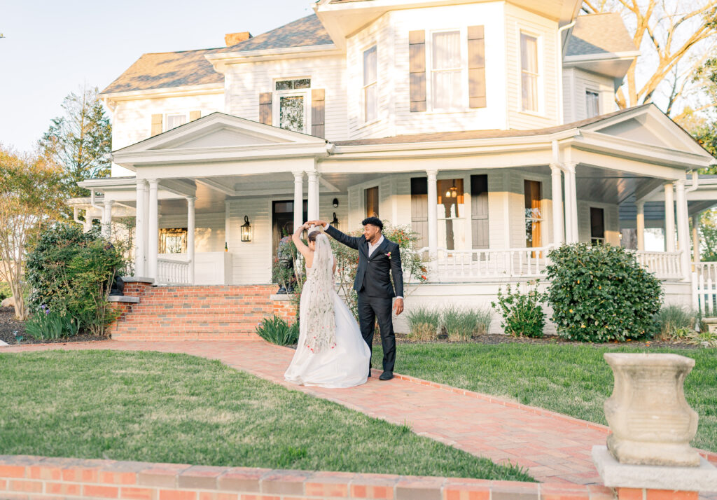 A couple dancing in front of The Victorian, a Wake Forest Wedding Venue by JoLynn Photography