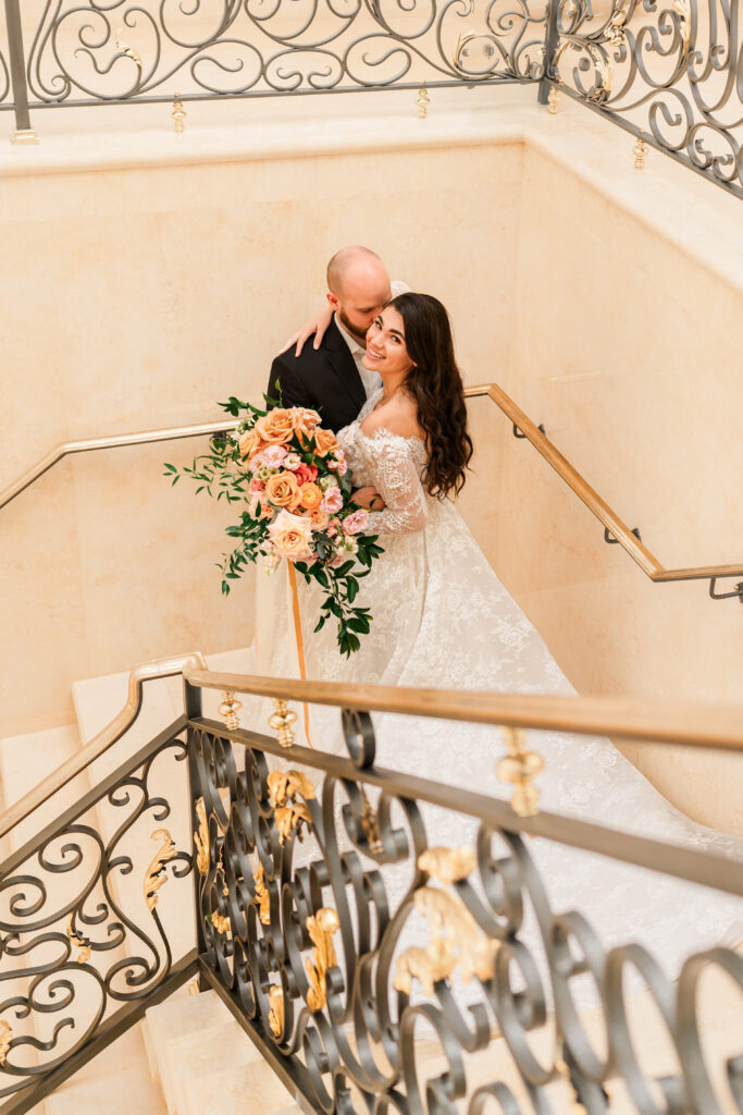 A couple standing in the stairway at The Oxbow Estate by JoLynn Photography