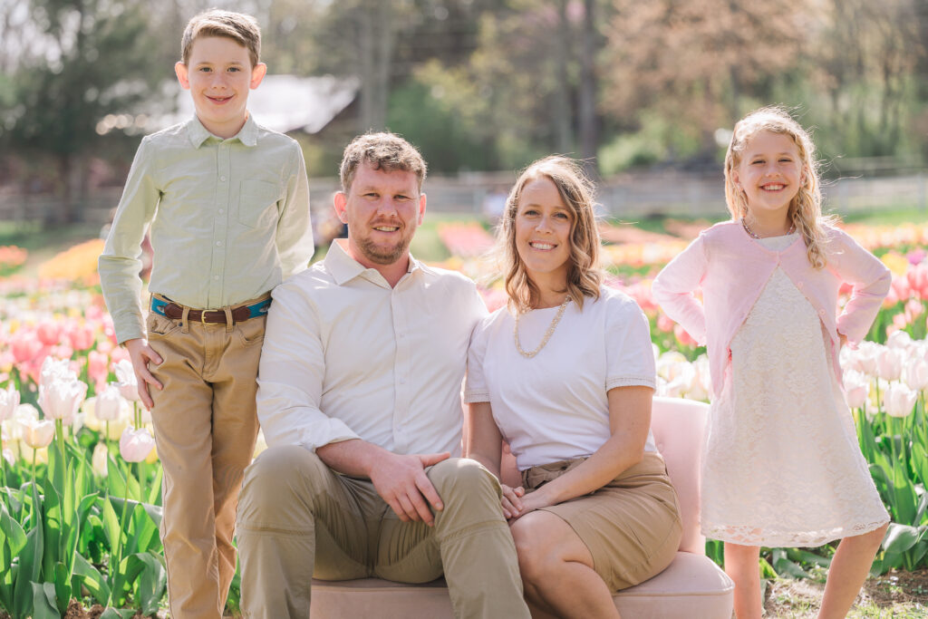 A happy family in front of endless rows of tulips at Dewberry Farms by a Greensboro family photographer, JoLynn Photography