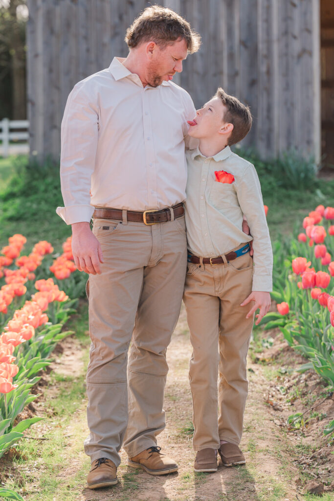A son and father having fun sticking out their tongues during their family spring portraits at Dewberry Farms enjoying their session with Greensboro family photographer, JoLynn Photography
