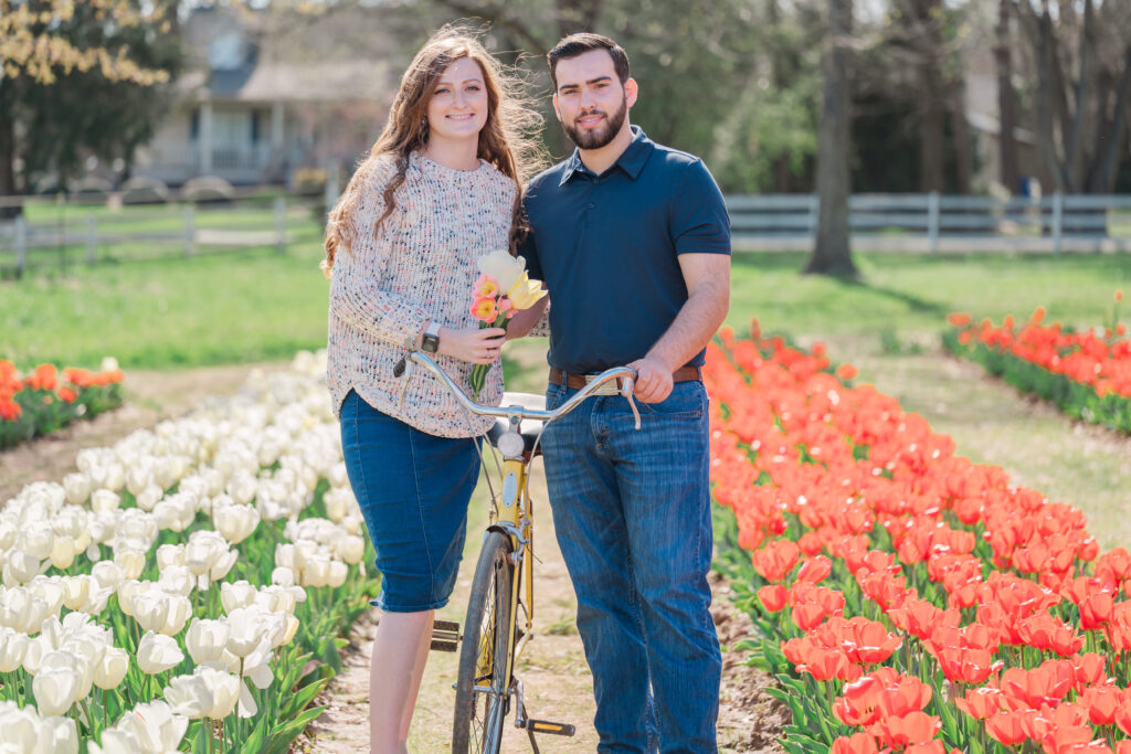 A loving engaged couple standing next to a bike at Dewberry Farms by JoLynn Photography, a Greensboro wedding photographer

