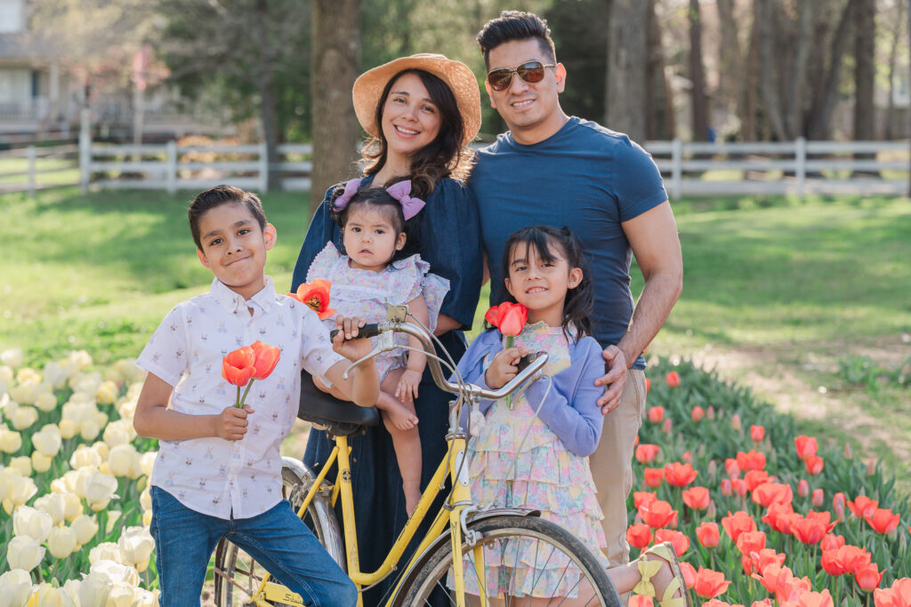 A happy family in tulips in  Wake Forest around a vintage bicycle enjoying their Wake Forest family photography session by JoLynn Photography