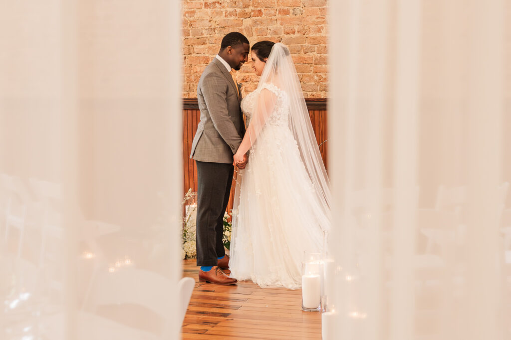 A bride and groom holding hands at the altar during their wedding day at a downtown Wake Forest venue by JoLynn Photography