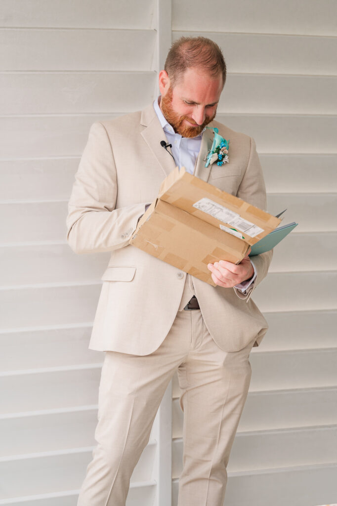 A groom opening a gift from his soon to be wife at their Atlantic beach wedding by JoLynn Photography