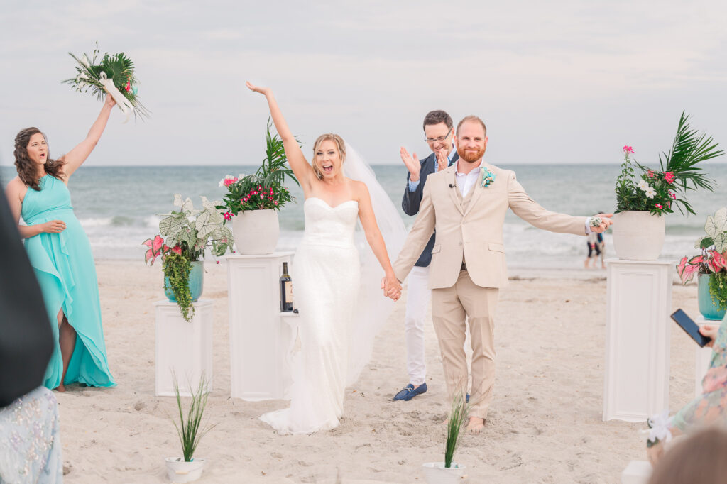 A happy newly married couple rejoicing after saying I Do at their Atlantic beach wedding by JoLynn Photography