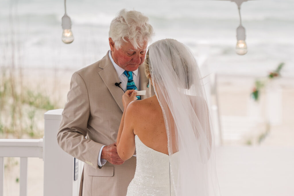 A bride helping her dad at her Atlantic beach wedding with his tie by JoLynn Photography