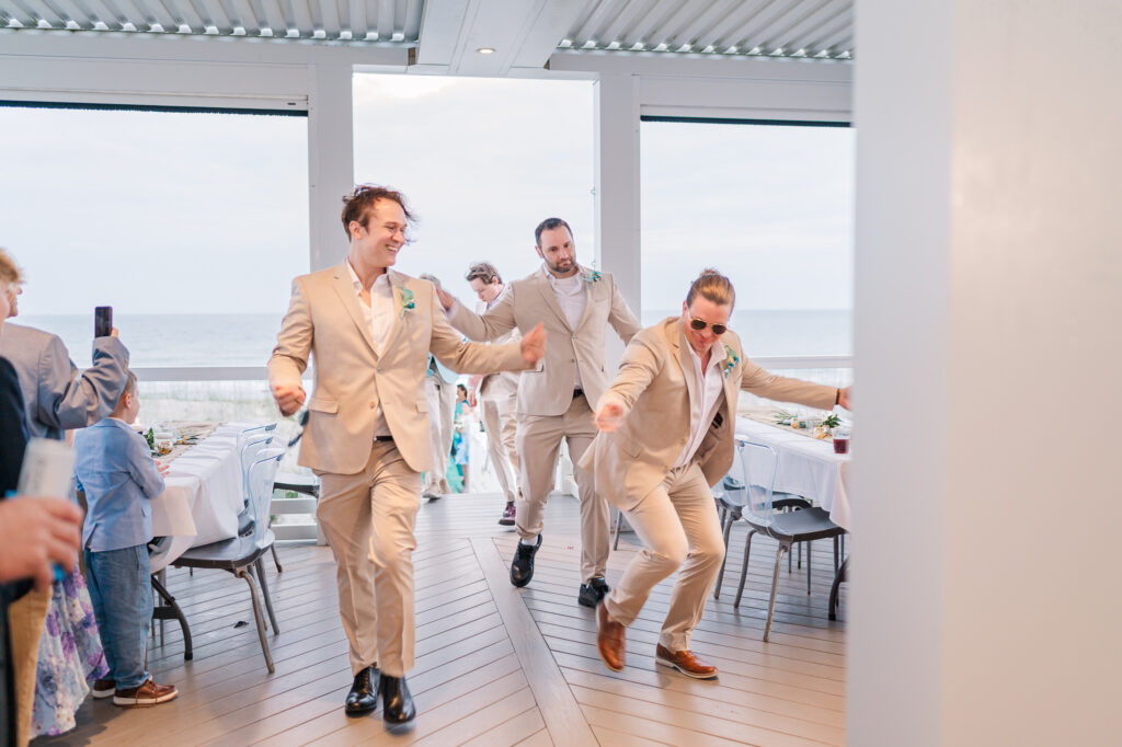 Three groomsmen entering a wedding reception dancing