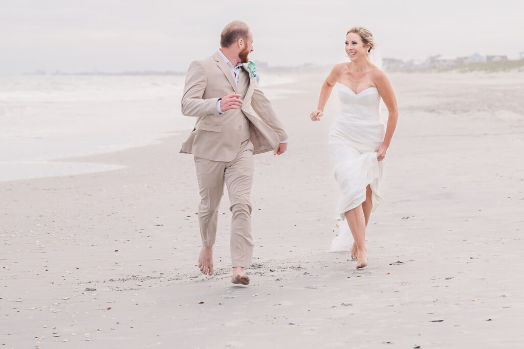 A bride and groom running down the beach at sunset by JoLynn Photography