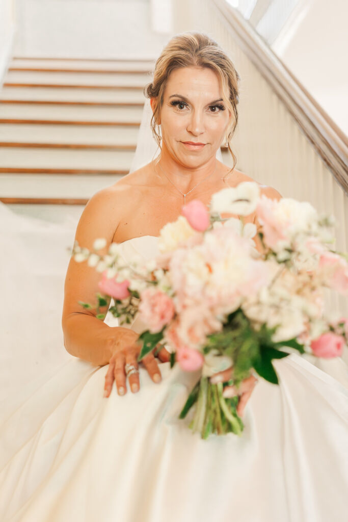 A smiling bride sitting on a staircase during her bridal portraits at Highrock Farms by JoLynn Photography 