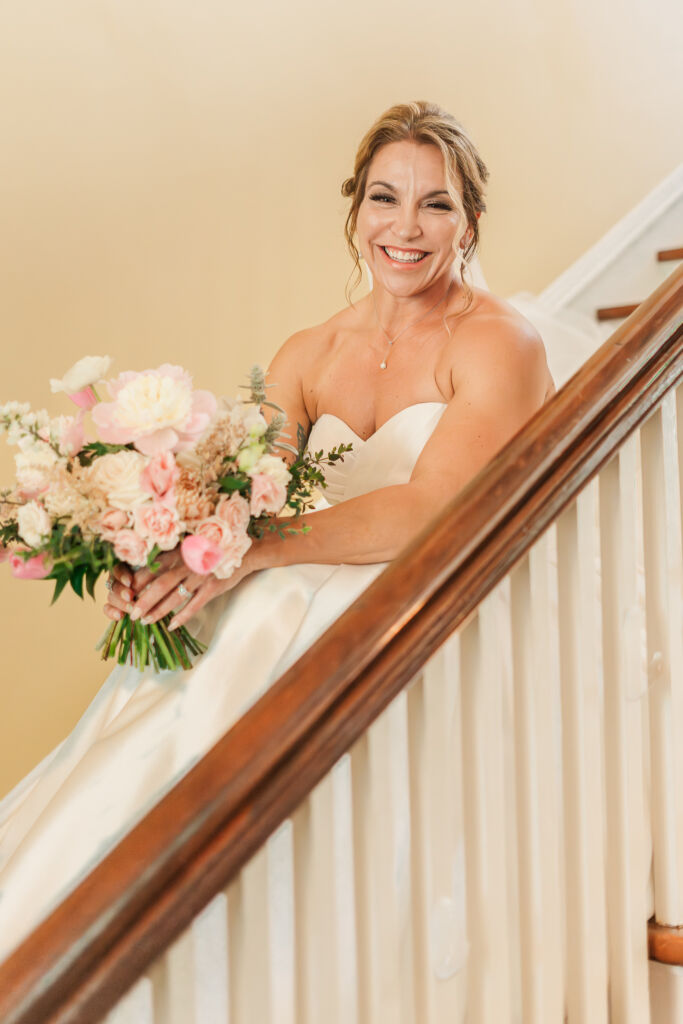 A laughing brunette bride on a staircase during her bridal portrait session by JoLynn Photography