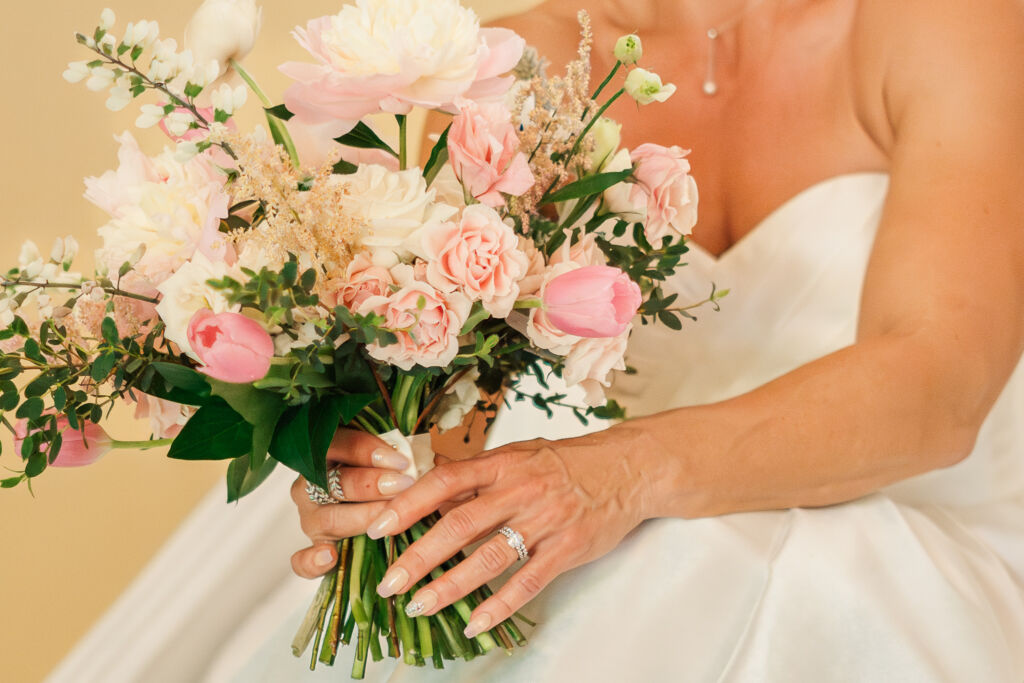 A close up picture of a pastel summer bridal bouquet  and her engagement ring