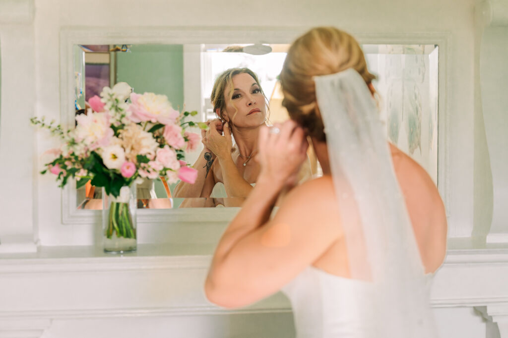 A stunning bride putting her wedding earrings on in the bridal bathroom at Highrock Farms by JoLynn Photography