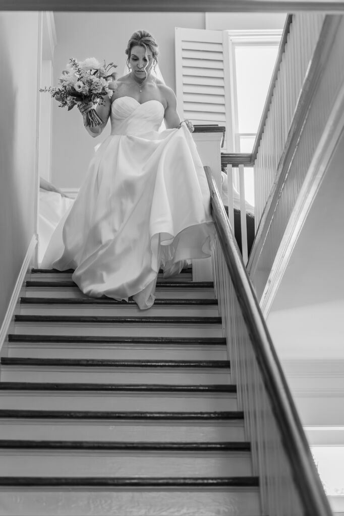 A bride walking down the grand staircase at Highrock Farms by JoLynn Photography