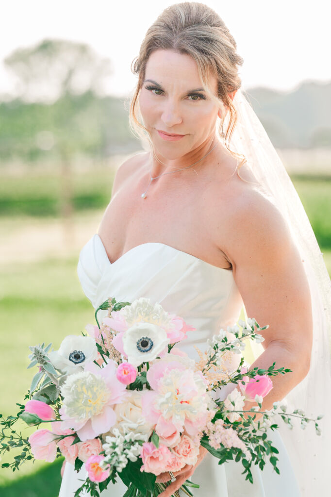 A serious bride at sunset holding her wedding bouquet during her bridal portrait session at Highrock Farms