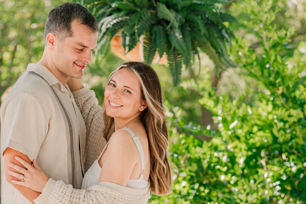 A couple embracing chest to chest on a white front porch in Wilmington enjoying their Sycamore Bend engagement by JoLynn Photography