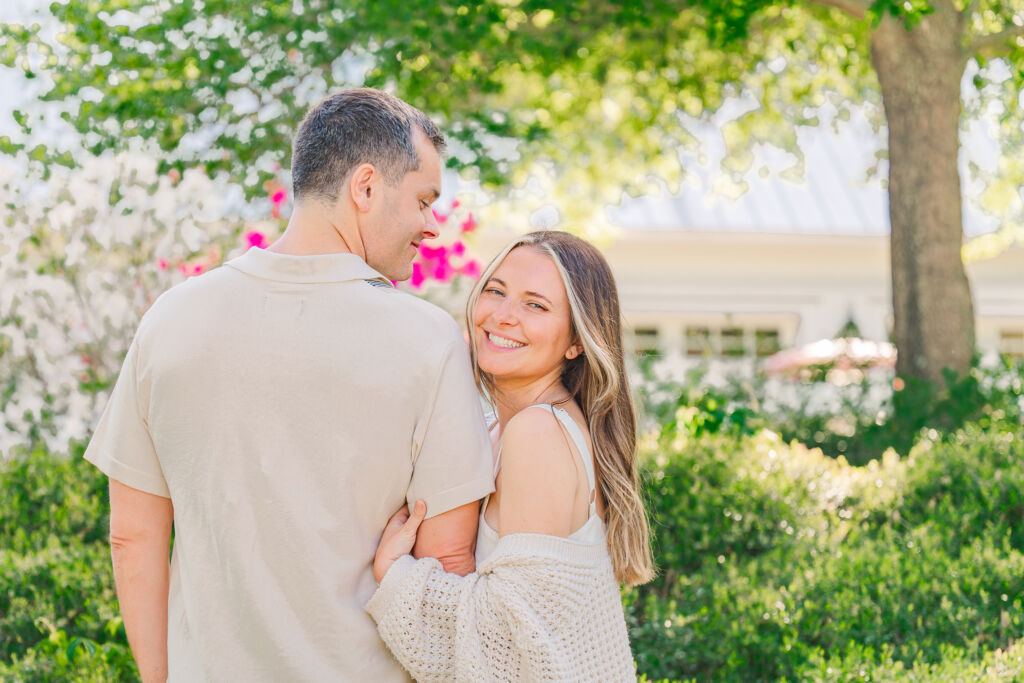 Smiles and hugs under a blooming azalea bush by a couple enjoying their Sycamore Bend engagement