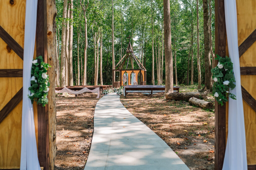 The wedding aisle entering a secluded wedding ceremony of the Enchanted Woods at The English Country Barn by JoLynn Photography