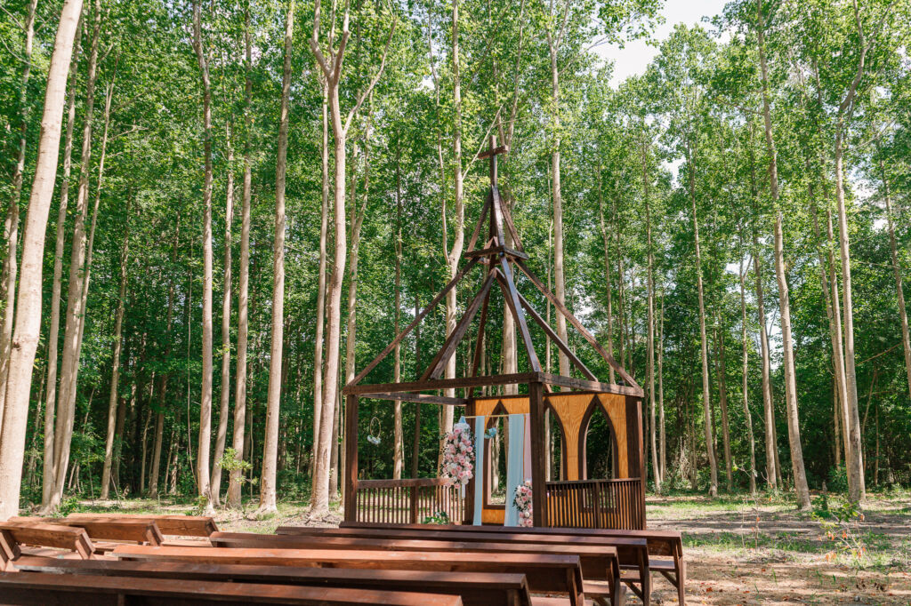 An outdoor wedding ceremony in the seclusion of the woods at The English Country Barn by JoLynn Photography