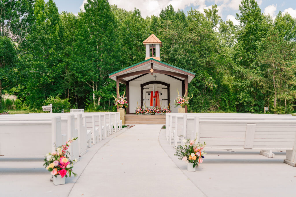 An aisle view of Somerset Gardens at The English Country Barn by JoLynn Photography on a June summer day