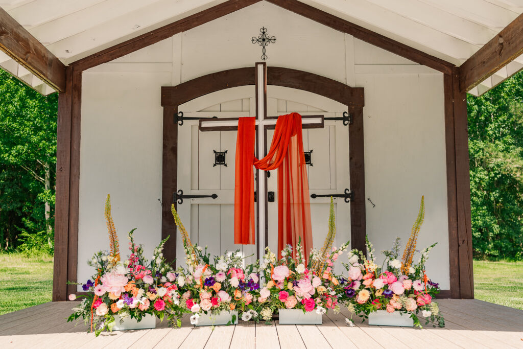 A cross on the stage of an outdoor wedding chapel at The English Country Barn