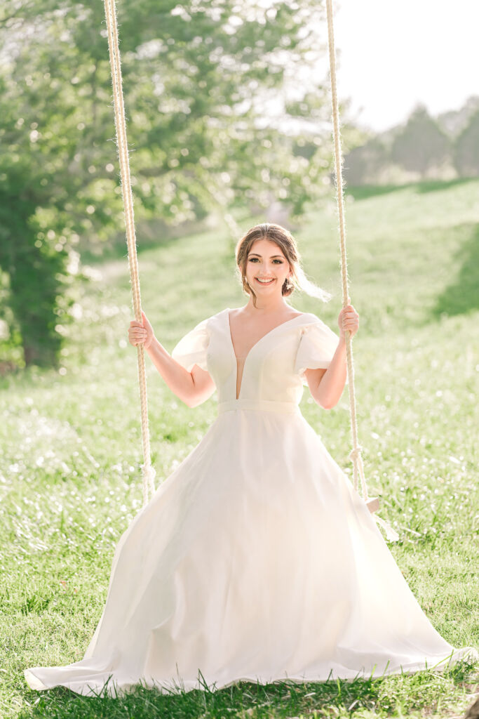 A playful brunette bride enjoying her summer outdoor bridal portrait session at Firefly Haven by JoLynn Photography