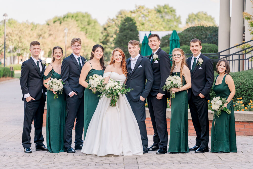 A wedding party with a bride and a groom in green and black colors on a fall afternoon at a Cary wedding venue by JoLynn Photography