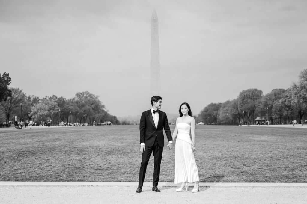 A loving happy Asian couple celebrating their spring engagement next to iconic DC monuments by Washington DC wedding photographer, JoLynn Photography