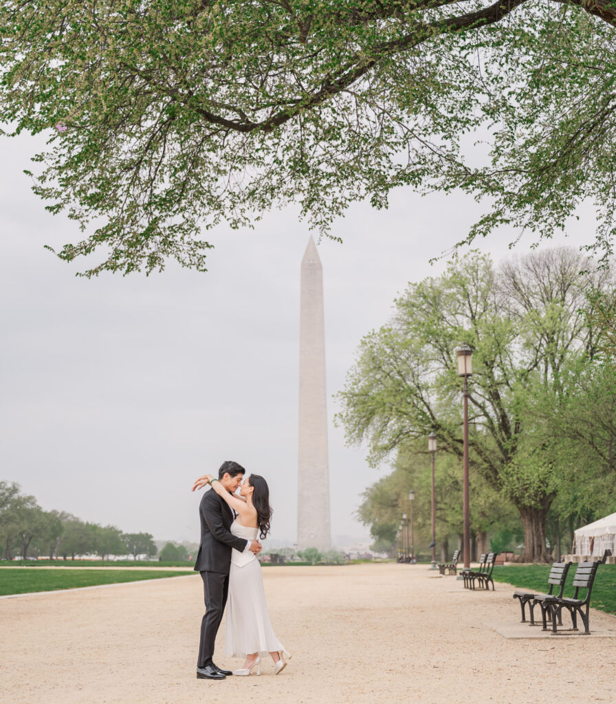 A loving happy Asian couple celebrating their spring engagement next to iconic DC monuments by Washington DC wedding photographer, JoLynn Photography