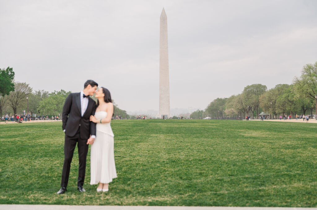 A loving happy Asian couple celebrating their spring engagement next to iconic DC monuments by Washington DC wedding photographer, JoLynn Photography