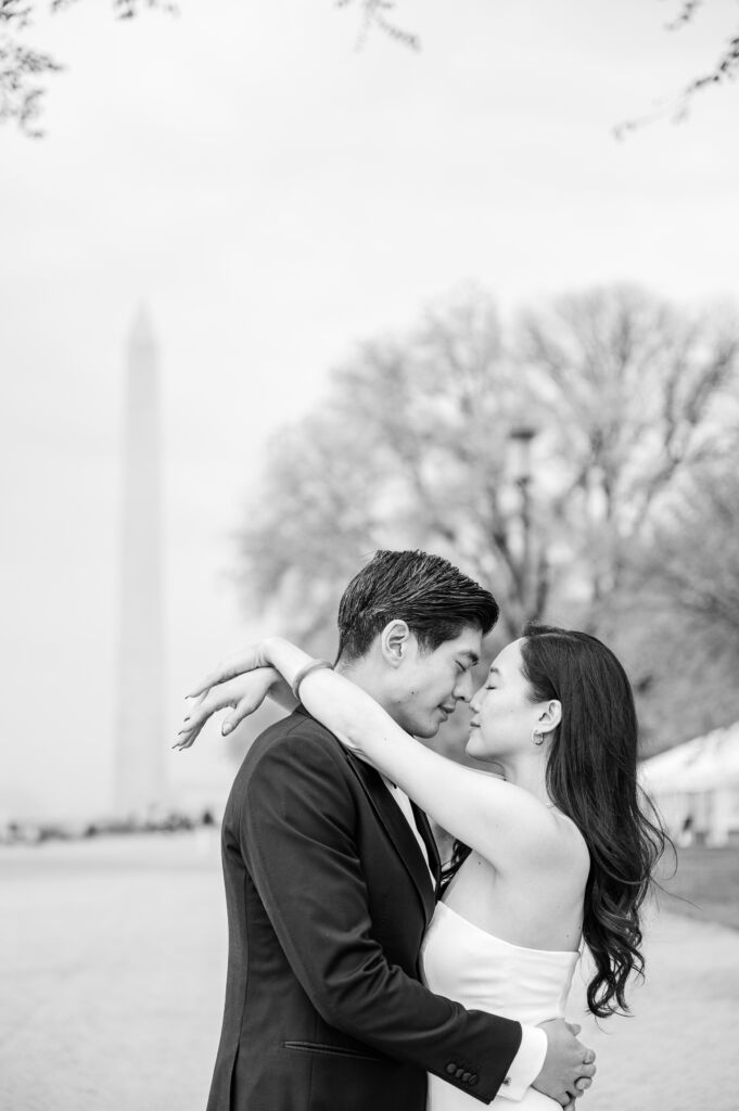 A loving happy Asian couple celebrating their spring engagement next to iconic DC monuments by Washington DC wedding photographer, JoLynn Photography