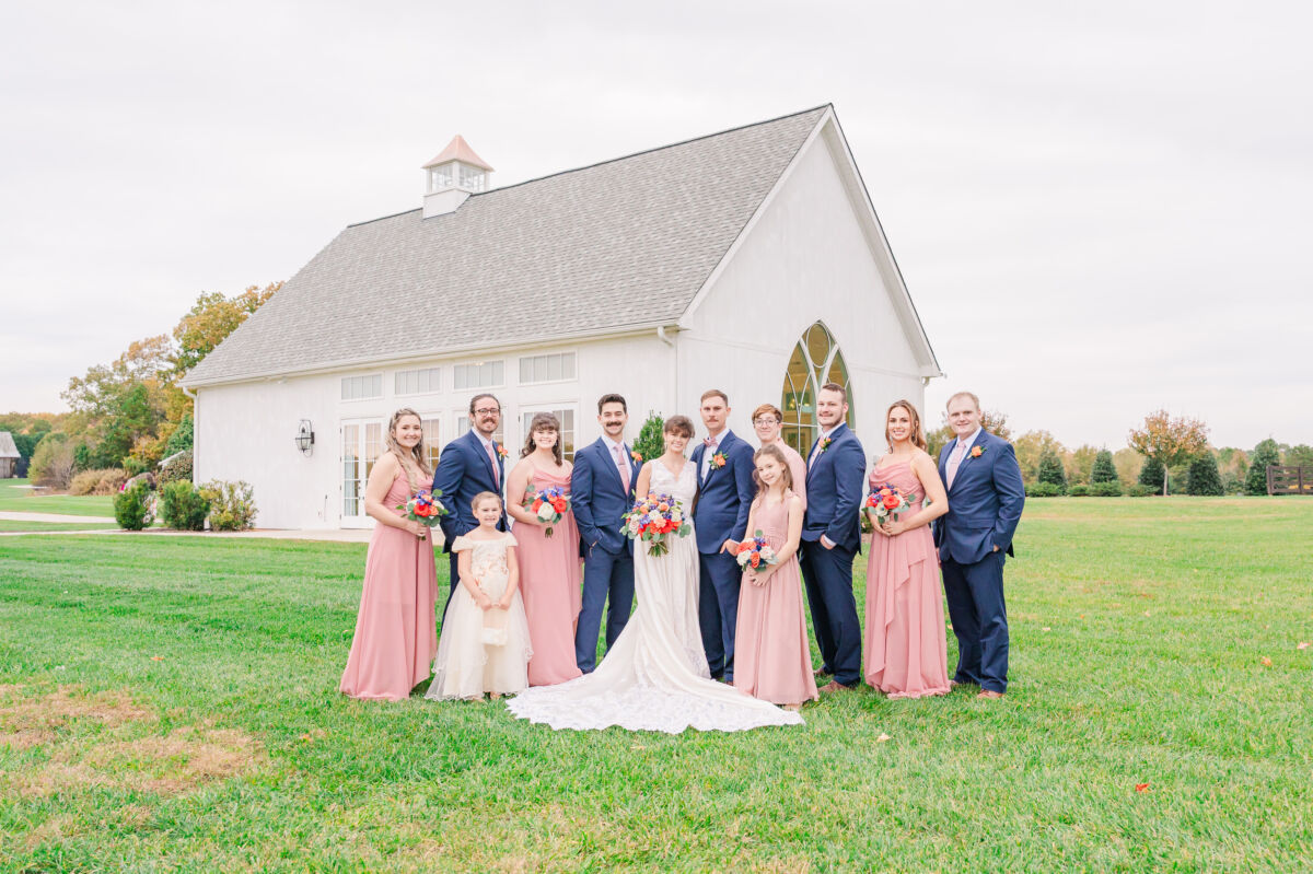 A beautiful wedding party in pink dresses and blue suits on a stunning fall wedding dat at Chickadee Hill Farms by JoLynn Photography