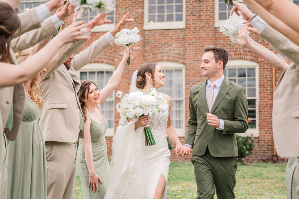 A couple running under the hands of their wedding party during their June wedding in Fredericksburg