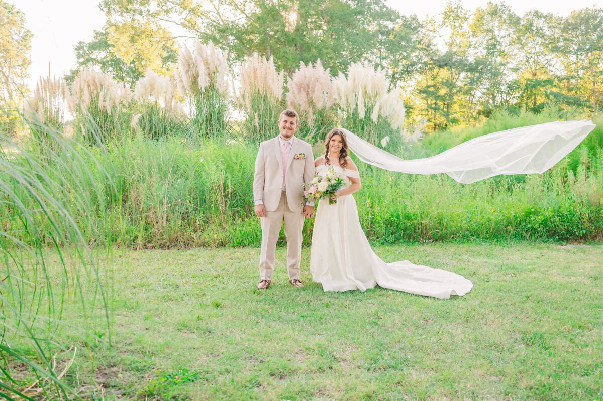 A loving couple dressed in tan, an array of pastels, and surrounded by garden greenery on their fall wedding day at an estate wedding venues North Carolina by JoLynn Photography
